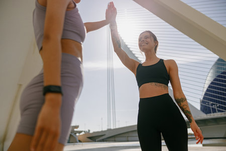 Happy female friends doing gesture of sport shake hand after exercising outside