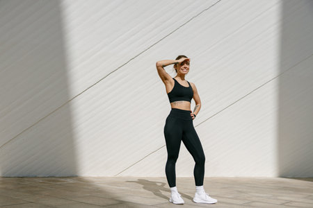 Young female athlete in sportswear have a rest after morning jogging outside and looks away