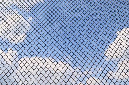 blue sky with clouds behind metallic net の写真素材