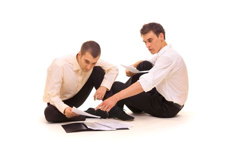 two businessmen sitting on the floor and scrutinizing documents. isolated on whiteの写真素材