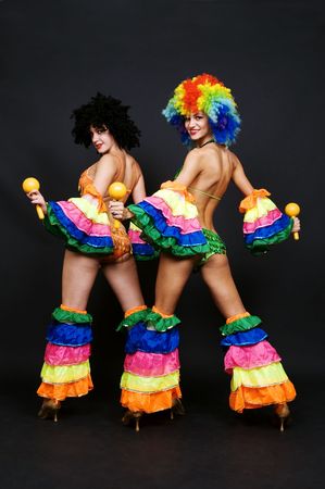 view from behind on two attractive dancers with maraca against dark background