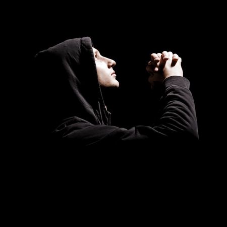 young man is praying against black backgroundの写真素材