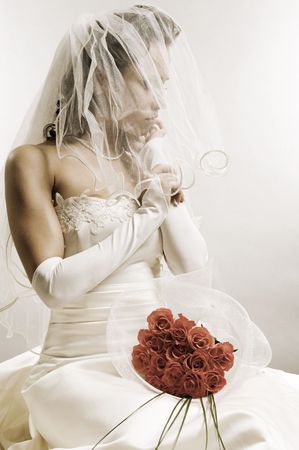thoughtful bride sitting with bunch of rosesの写真素材