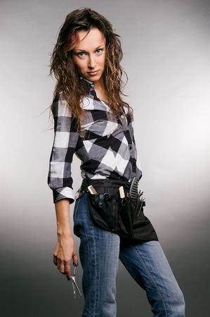 attractive hairdresser with scissors in her hand. studio shot over grey backgroundの写真素材