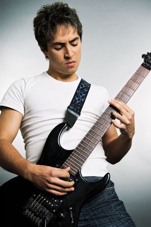 young man playing on the guitar over grey backgroundの写真素材