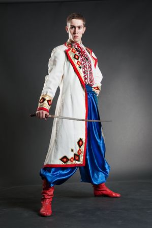 young handsome cossack with sabre over dark background