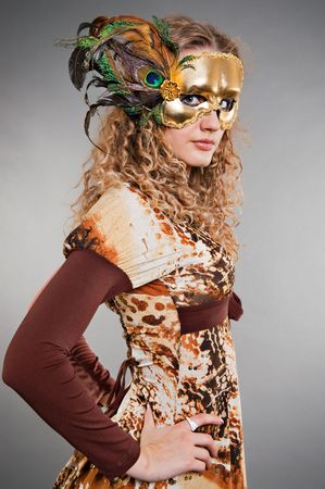 beautiful blond in golden mask posing against dark backgroundの写真素材