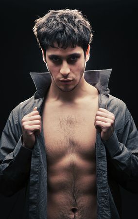 handsome man taking of his shirt against black backgroundの写真素材