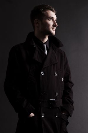 serious man in black cloak against dark backgroundの写真素材