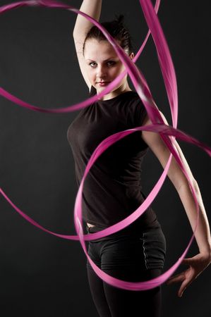 beautiful dancer with red ribbon against dark backgroundの写真素材