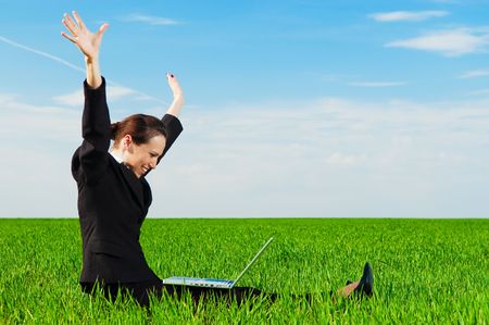 successful businesswoman with computer sitting at the green fieldの写真素材
