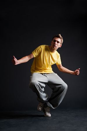 breakdancer in yellow t-shirt dancing against dark backgroundの写真素材