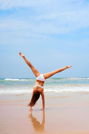 woman in white swimsuit doing cartwheel at the beachの写真素材