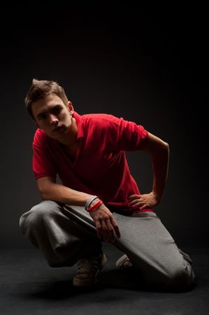 breakdancer in red t-shirt sitting against dark backgroundの写真素材