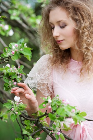 attractive young woman looking at small flower on treeの写真素材