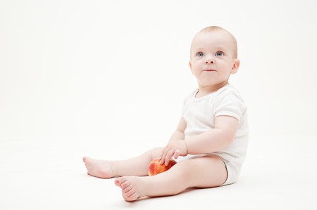 pretty baby with apple sitting on the floorの写真素材