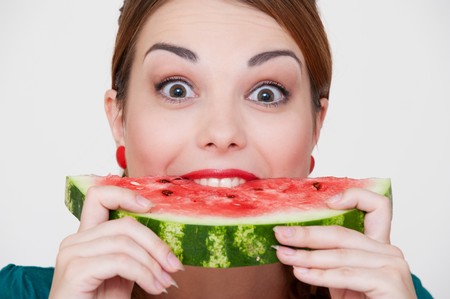 happy woman biting slice of watermelon over grey background の写真素材