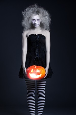 portrait of ghost with orange pumpkin over dark backgroundの写真素材