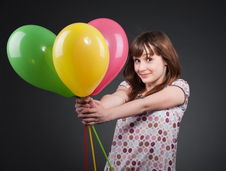 portrait of happy girl with balloons over dark backgroundの写真素材