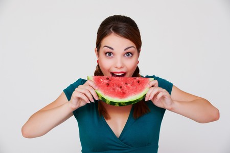 happy woman biting slice of watermelon over grey background の写真素材