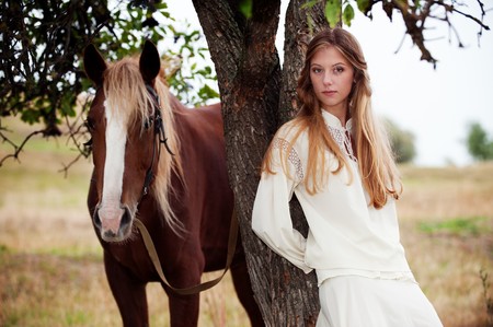 outdoor portrait of pretty woman with brown horseの写真素材