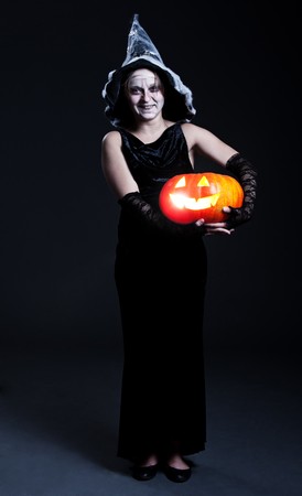 portrait of witch in hat with orange pumpkin. halloween theme の写真素材