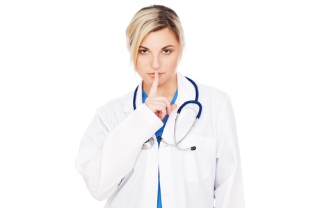 serious doctor making silence sign over grey background の写真素材