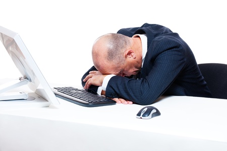 tired businessman sleeping on his workplace over white backgroundの写真素材