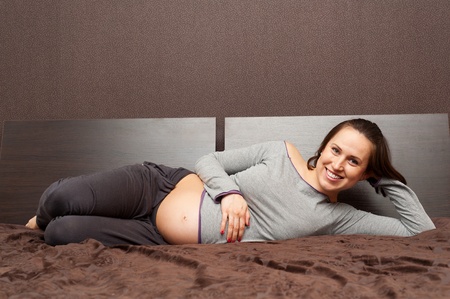 smiley pregnant woman lying on bed and relaxing の写真素材