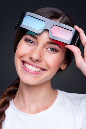 cheerful young woman with stereo glasses over dark backgroundの写真素材