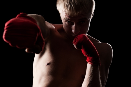 portrait of caucasian boxer with red bandage on hands. studio shot over dark backgroundの写真素材