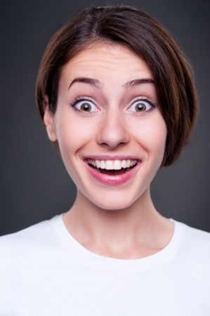 portrait of amazed and happy young woman over dark backgroundの写真素材
