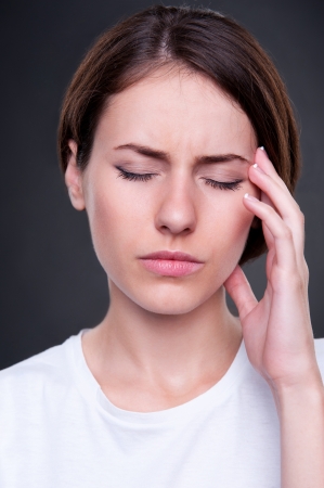 portrait of young woman have a headache. studio shot over dark backgroundの写真素材