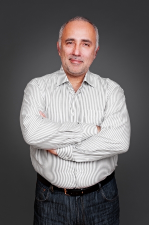 successful senior man with folded hands standing over grey backgroundの写真素材