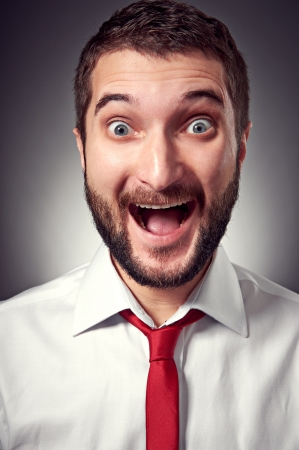 portrait of excited young man with beard over grey backgroundの写真素材