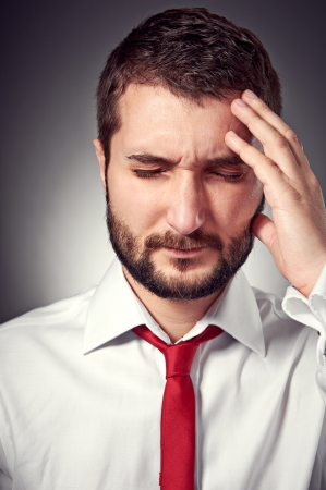portrait of man with headache over grey backgroundの写真素材