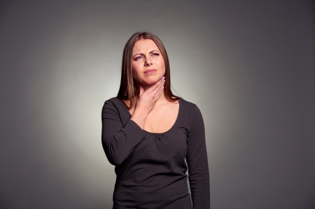 unhappy woman have a throat pain. studio shot over dark backgroundの写真素材
