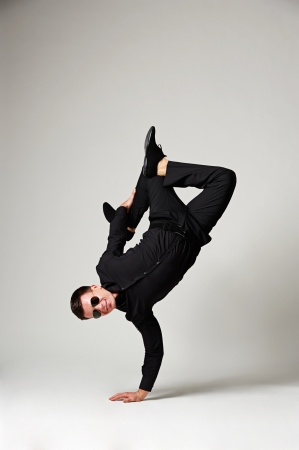 stylish man in formal wear and sunglasses standing on one handの写真素材