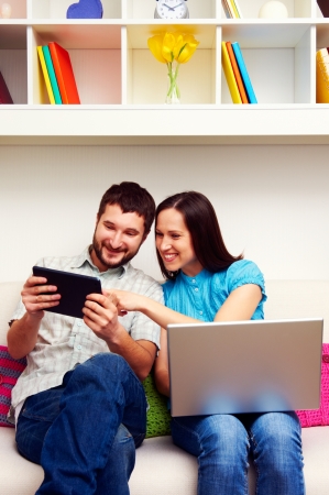 happy couple sitting on sofa and looking at the tablet pcの写真素材