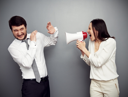young businesswoman screaming in megaphone at the manの写真素材