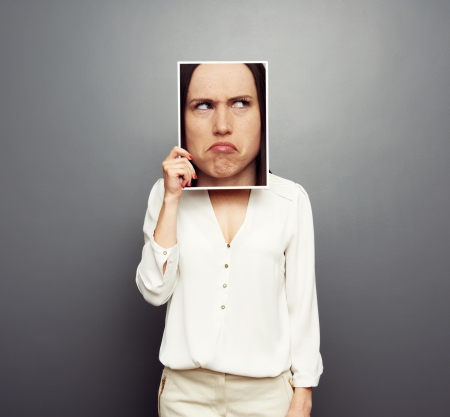 young woman covering image with big pensive face. concept photo over grey backgroundの写真素材