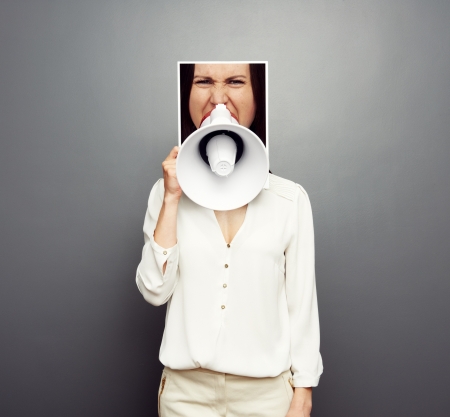 concept photo of young female screaming in megaphone over dark backgroundの写真素材