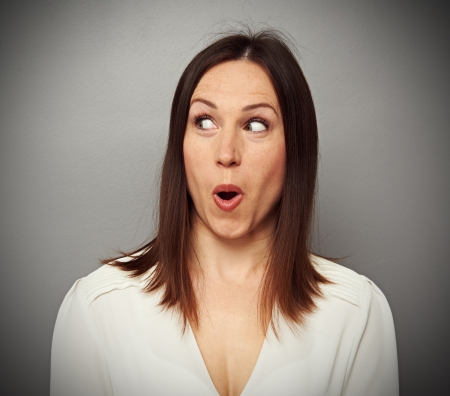 amazed woman looking at something over dark backgroundの写真素材