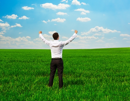 back view of happy and successful man on the green fieldの写真素材