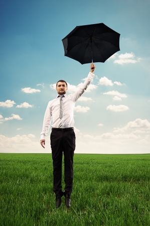 young businessman flying with black umbrellaの写真素材