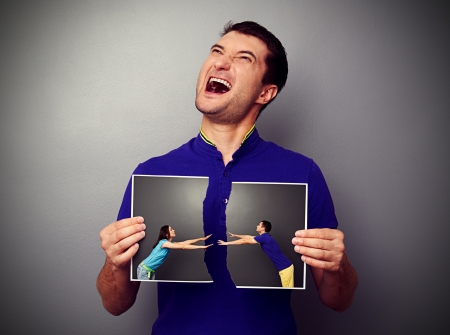 man holding the torn photo with couple and gibing over dark backgroundの写真素材
