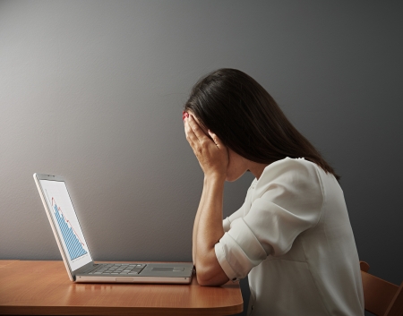 depressed woman covering her face by the hands over dark wallの写真素材