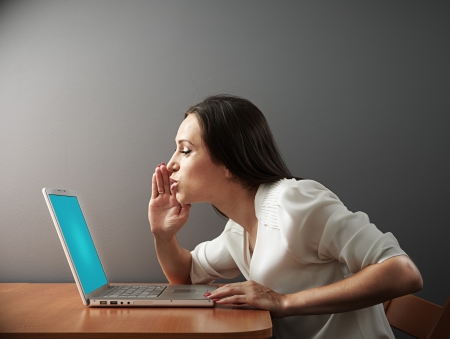 young woman whispering secrets to her laptopの写真素材