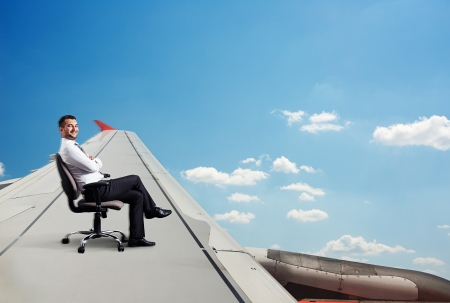 happy businessman sitting on chair and flyingの写真素材