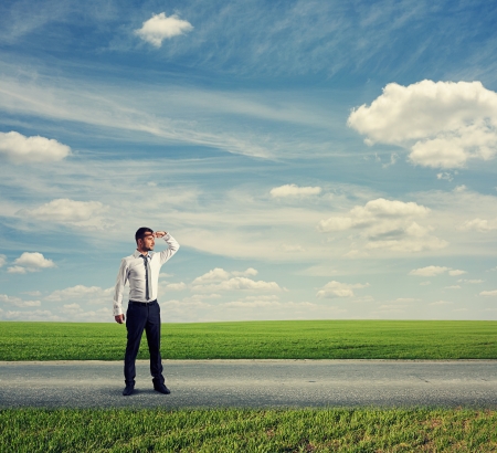 serious businessman standing on road and looking forwardの写真素材